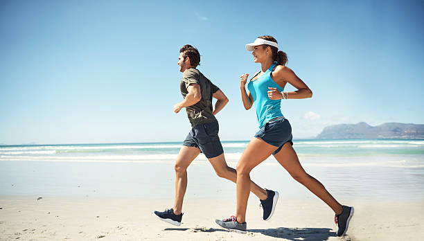 Shot of a young couple running along the beach together