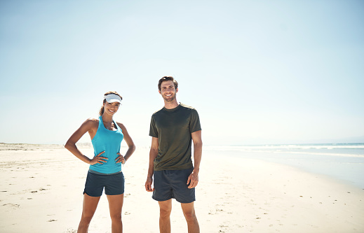 Portrait of a sporty young couple standing on the beach together