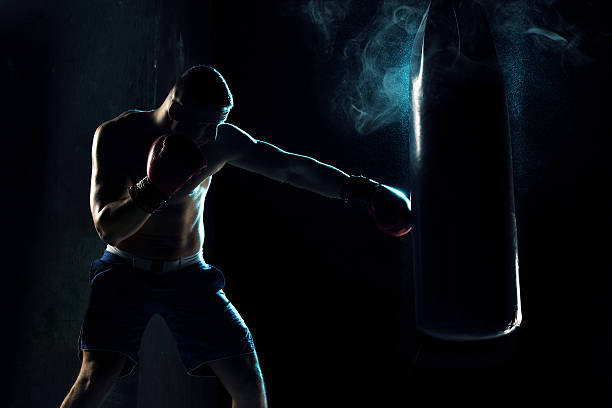 boxeador masculino de boxeo en bolsa de perforación - kickboxing fotografías e imágenes de stock