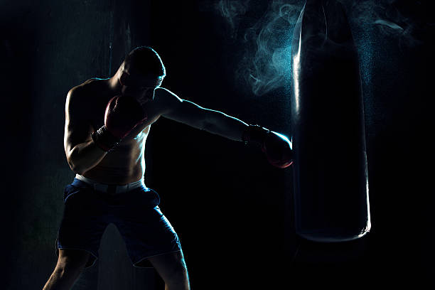 male boxer boxing in punching bag - kickboxing imagens e fotografias de stock