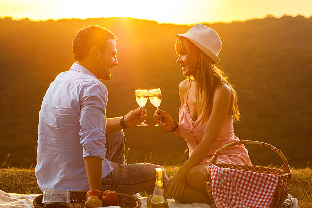 istock Smiling couple toasting with wine on picnic at sunset. 621500400