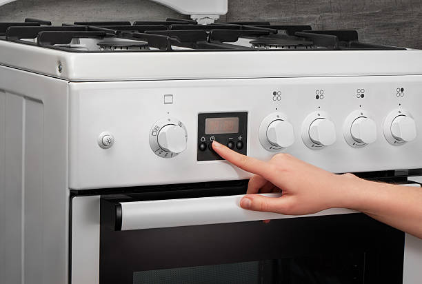 istock Female hand turning on white kitchen gas stove on gray 621501076