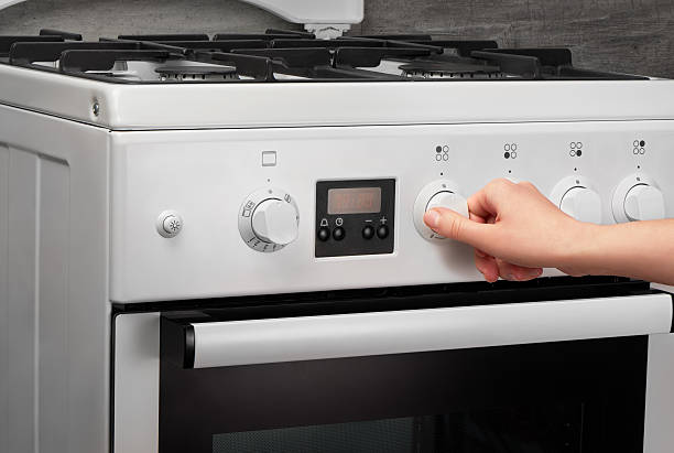 istock Female hand turning on white kitchen gas stove on gray 621501130