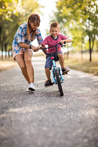istock Smiling mother teaching her son to ride bicycle in nature. 621501418