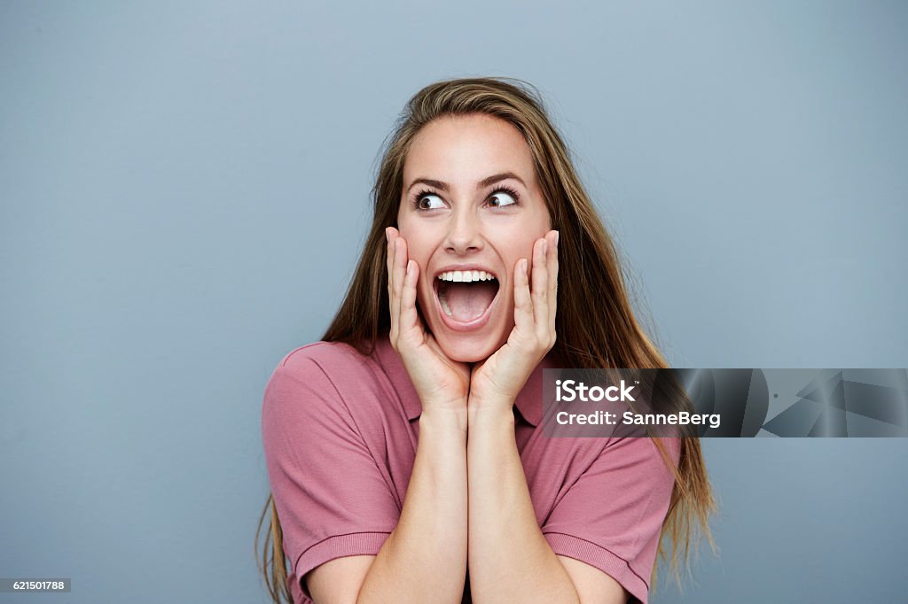 Surprised and ecstatic woman in pink, studio shot Head In Hands Stock Photo