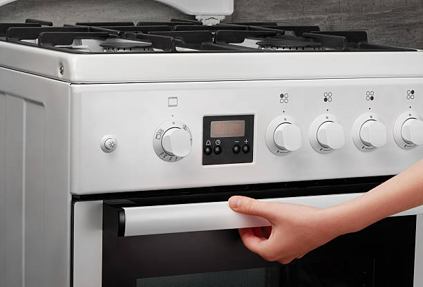 istock Female hand opening oven in white kitchen stove on gray 621502006