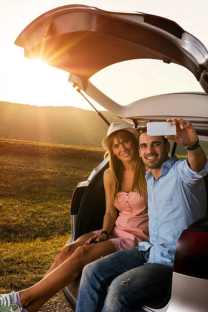 istock Smiling couple taking selfie with mobile phone on road trip. 621502412