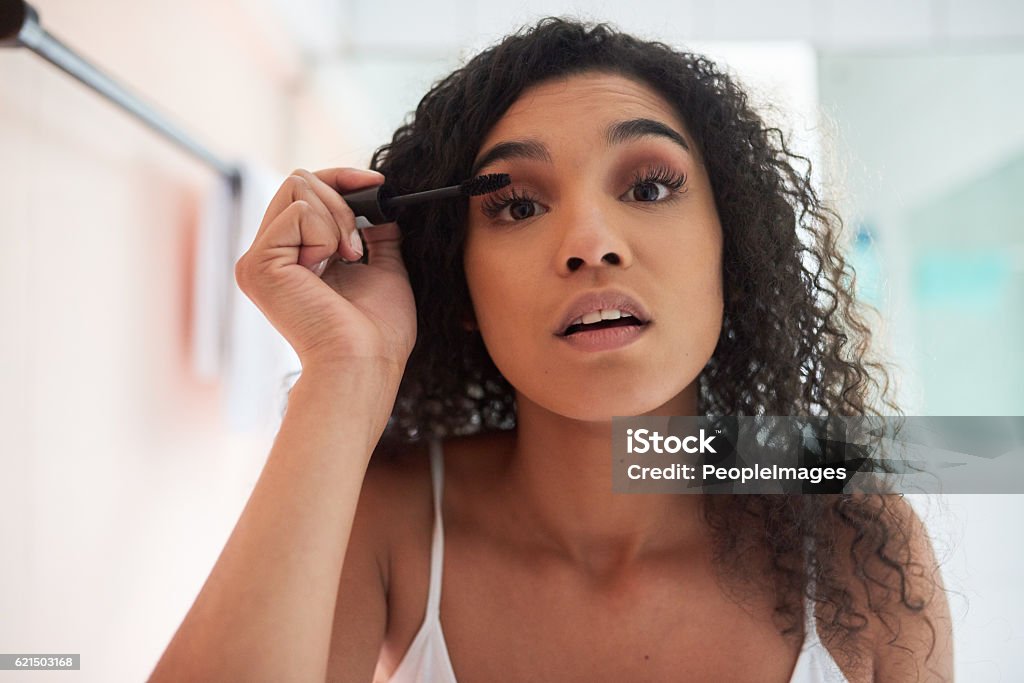 Getting ready for the day Portrait of an attractive young woman applying mascara in the bathroom Mascara Stock Photo