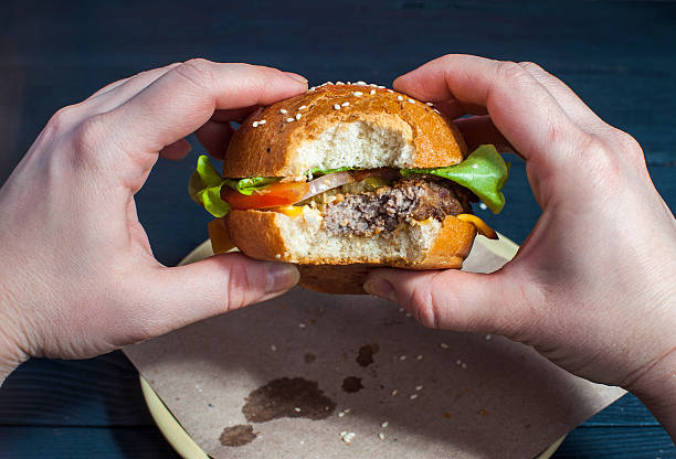 istock Fresh hamburger with vegetables in female hands 621503394