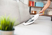 Woman with handheld vacuum cleaning on sofa