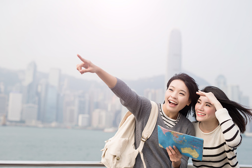 two beauty woman take map and show something in hongkong