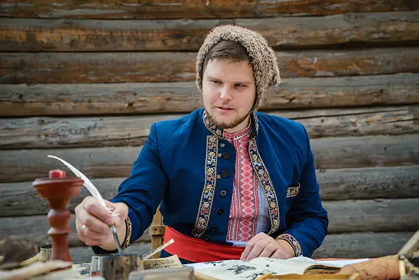 man in traditional ukrainian dress with hat is writing