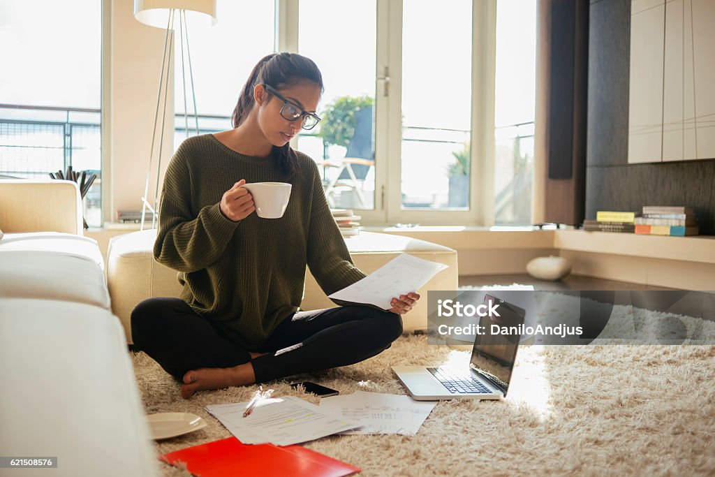 jeune femme lisant des documents dans son salon, - Photo de Chaleur libre de droits