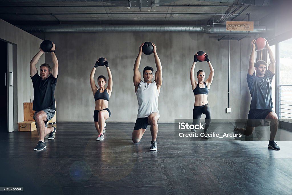 Because working out on your own can be a drag... Shot of a fitness group having a workout session at the gym Exercising Stock Photo