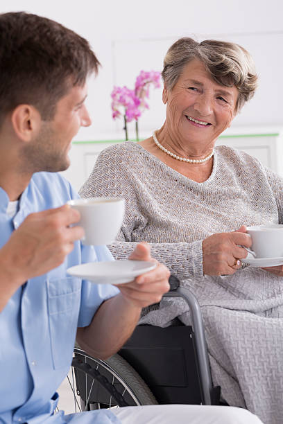 istock Senior woman drinking tea with her caregiver 621570168