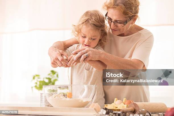 Child Breaking The Egg Into A Bowl Stock Photo - Download Image Now - Grandmother, Cooking, Baking