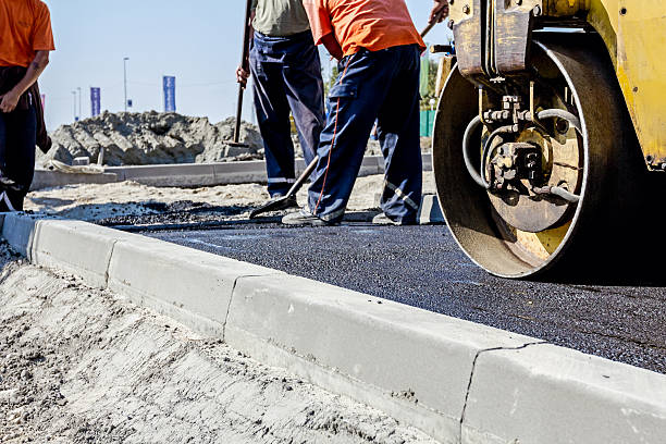 Hot asphalt is spreading with steamroller during road works Zrenjanin, Vojvodina, Serbia - September 23, 2015: Building activities during construction of the large complex shopping mall "AVIV PARK" in Zrenjanin city.  kerbstone stock pictures, royalty-free photos & images