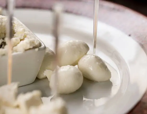 Close up of slices of mozzarella on a plate with skewers.