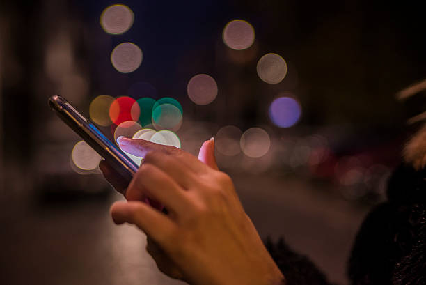 istock Woman using her Mobile-Phone in the street, night light Background 621574890