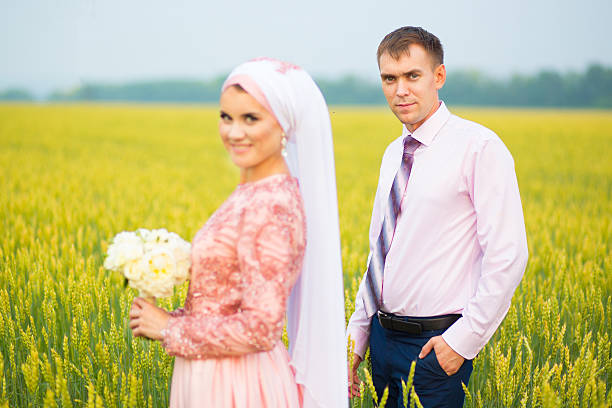 retrato sonriente de una joven pareja islámica en el campo de girasoles - cut flowers women field single flower fotografías e imágenes de stock