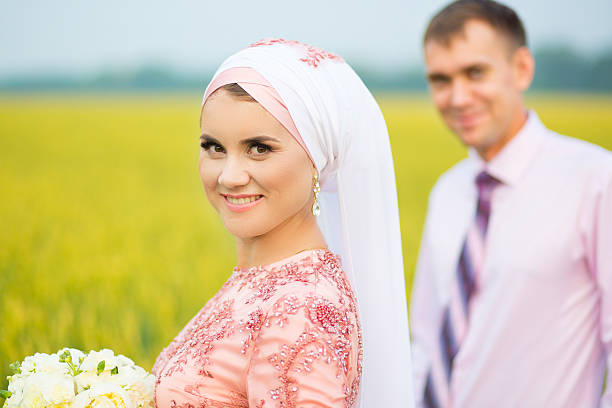 retrato sonriente de una joven pareja islámica en el campo de girasoles - cut flowers women field single flower fotografías e imágenes de stock