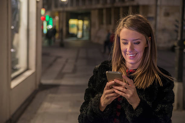 istock Female using her mobile phone, city skyline night light background 621576150
