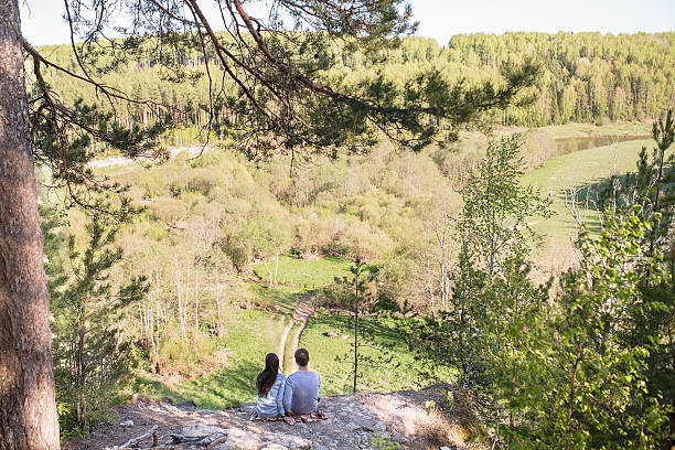 istock Young couple sitting on the edge of a cliff 621578568
