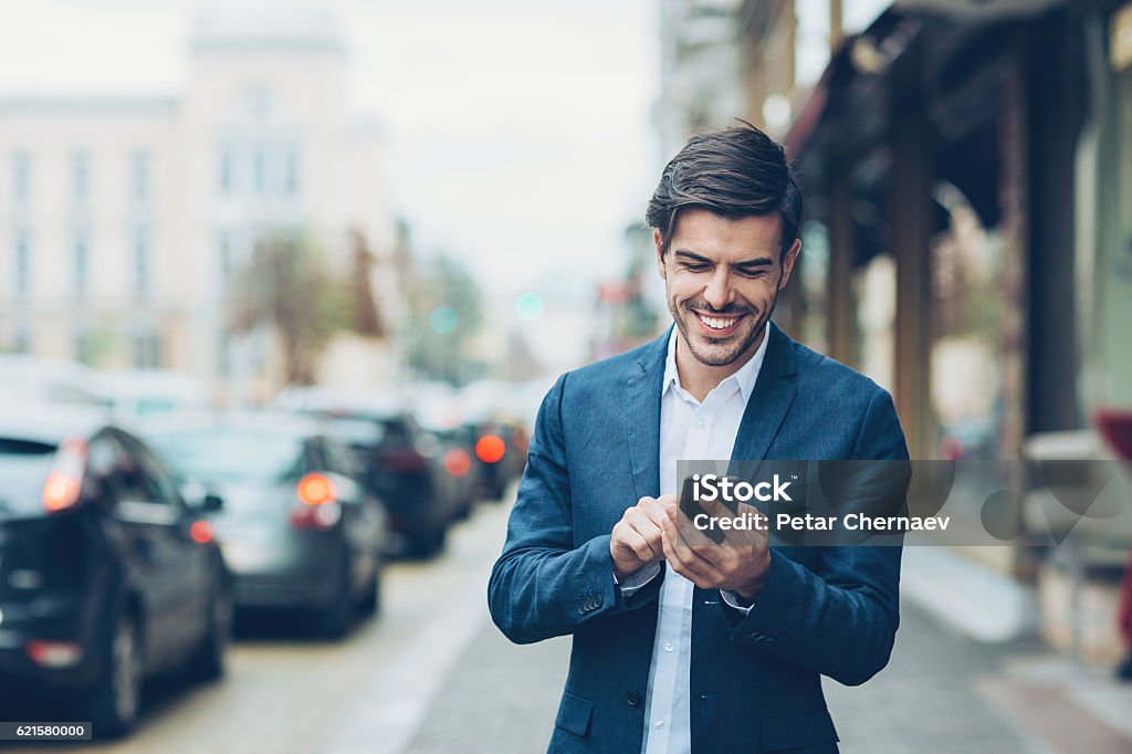 Manager Smiling businessman with smart phone outdoors on the street, with copy space. Businessman Stock Photo