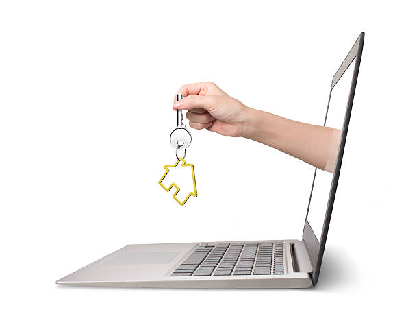 istock Hand holding house key comes from laptop screen 621582428