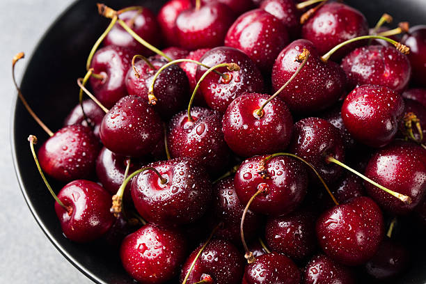 istock Fresh ripe black cherries in a black bowl Grey background 621582808
