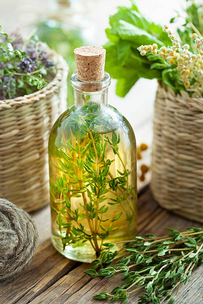 тимьян эфирное масло или настой и корзину целебных трав. - vinegar bottle herb white стоковые фото и изображения