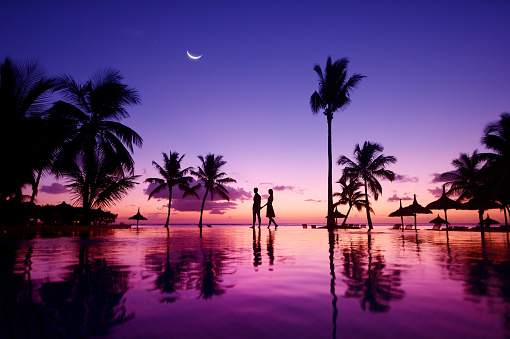 Silhouettes of young couple at scenic sunset on tropical beach