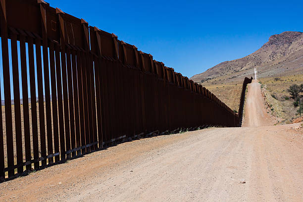 Border fence Capture of the border fence between USA and Mexico. A long never ending road with a metal fence on a side jeff goulden border security stock pictures, royalty-free photos & images