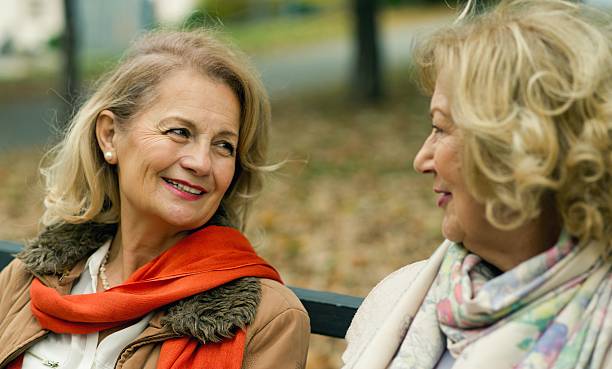 istock Two mature friends talking at the park. 621589330