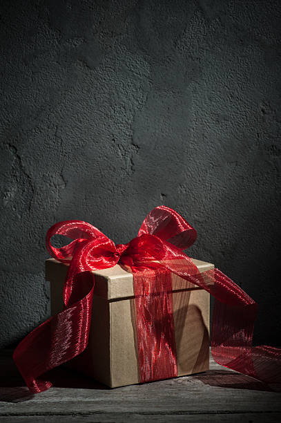 istock Craft paper gift box with red bow on wood table 621589476
