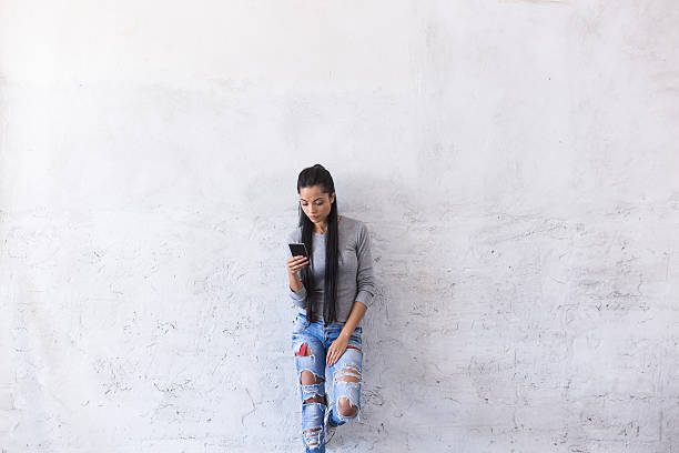 istock Young asian woman leaning back on blank wall 621593676
