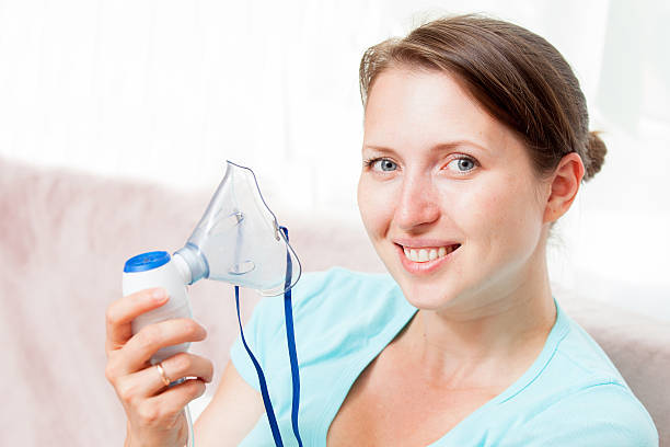 istock Young woman doing inhalation with a nebulizer at home 621596208