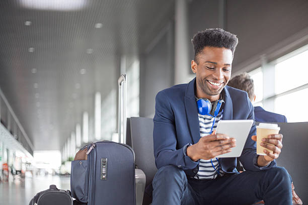 デジタルタブレット空港ラウンジを使用した若いアフリカ人 - travel airport business people traveling ストックフォトと画像