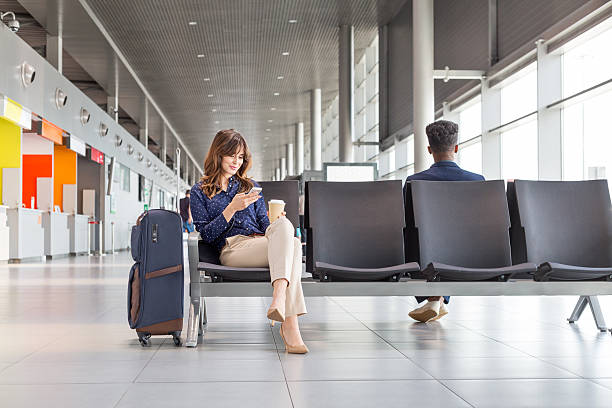 kobieta czekająca na lot w poczekalni na lotnisku - airport people traveling business travel travel zdjęcia i obrazy z banku zdjęć