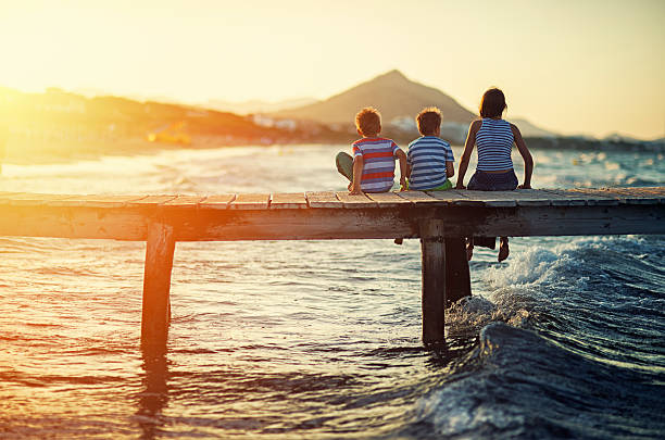 Summer vacations - kids sitting on sea pier