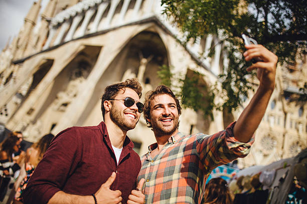 Tourists Taking a Selfie in Barcelona Two male friends taking a selfie in Barcelona in front of La Sagrada Familia. basilica photos stock pictures, royalty-free photos & images