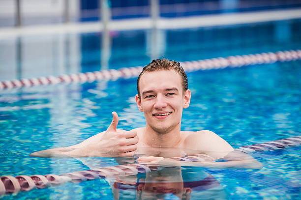 istock Young happy man in the swimming pool gesturing thumb up 621601340