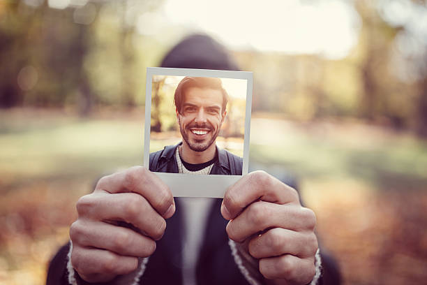Young man showing instant photo Smiling man showing self photo instant camera photos stock pictures, royalty-free photos & images