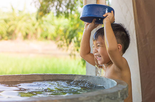 Asian village boy is taking a bath in water well.
