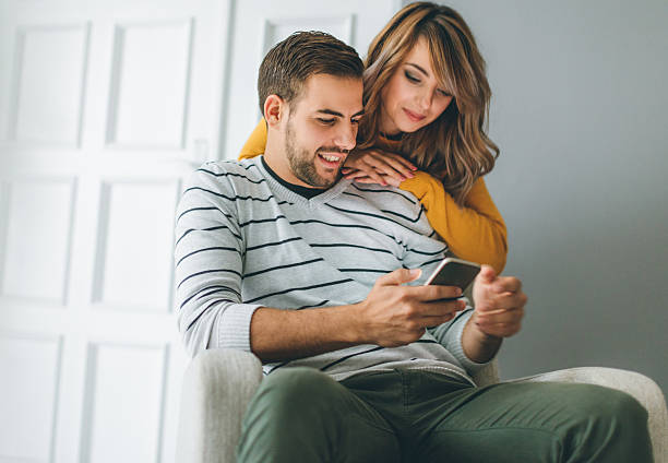 istock Beautiful young couple looking at smartphone 621609682