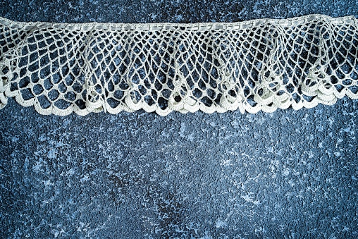 Crochet lace on blue cement background with copy space
