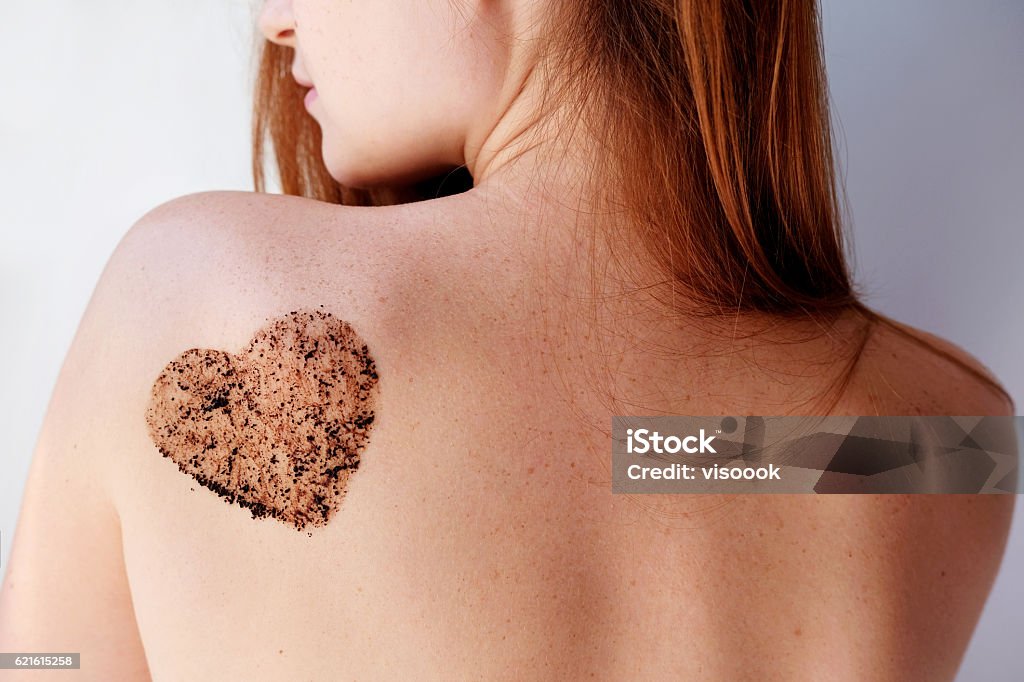 Woman with coffee scrub in a heart shape on back. Close up woman with coffee scrub in a heart shape on her back and shoulder Exfoliation Stock Photo