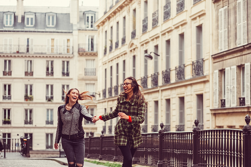 Enthusiastic friends running at the city street in Paris