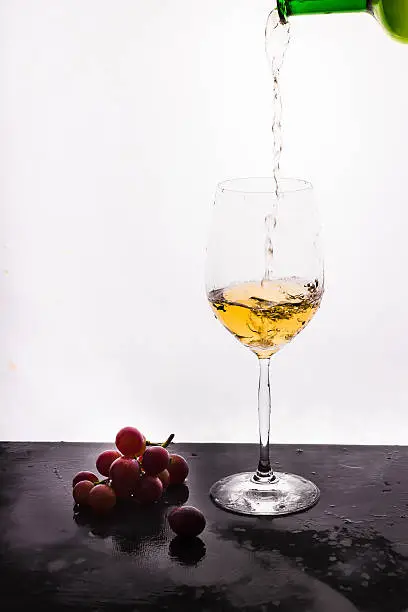 Flowing wine on white background and grape. Selective focus.