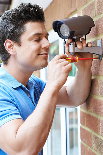 istock Security Consultant Fitting Camera To House Wall 621615776